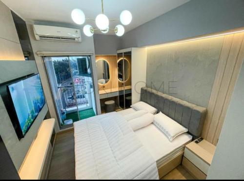ein Schlafzimmer mit einem großen weißen Bett und einem TV in der Unterkunft Apartement M-Town Avery Type Studio Gading Serpong Tangerang by HokiHome in Tangerang