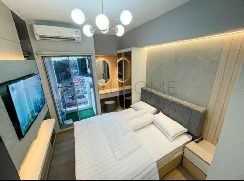 ein Schlafzimmer mit einem großen weißen Bett und einem Fernseher in der Unterkunft Apartement M-Town Avery Type Studio Gading Serpong Tangerang by HokiHome in Tangerang