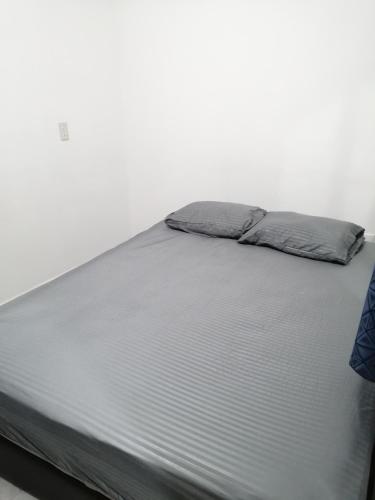 Una cama con sábanas grises y almohadas. en Departamento en Tonala, en Guadalajara