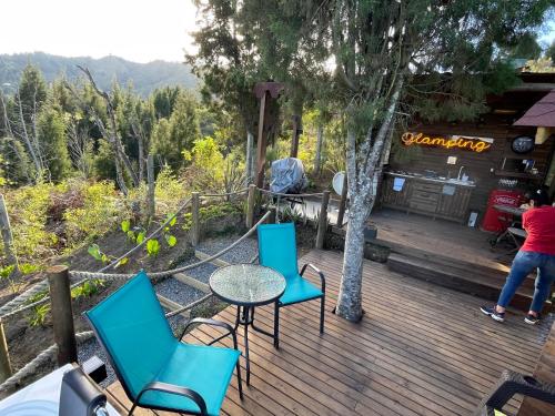 a wooden deck with chairs and a table and a tree at Entre-pinos Glamping WiFi Vista 360º in Guarne