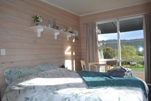 um quarto com uma cama e uma grande janela em Manuka Views - Close to Thermal Hot Pools em Kaukapakapa