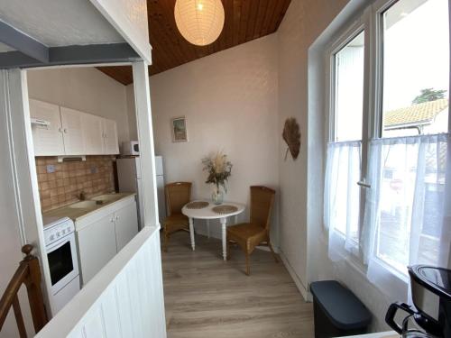 une petite cuisine avec une table et une fenêtre dans l'établissement Appartement cosy à Fouras: 1 chambre, proche commerces et plages, Wifi, TV, cuisine équipée - FR-1-709-70, à Fouras