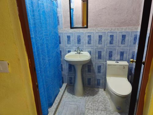 a blue tiled bathroom with a toilet and a sink at Hotel Posada Santa Elena in Parras de la Fuente