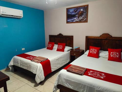 Habitación de hotel con 2 camas con almohadas rojas en Hotel Posada Santa Elena en Parras de la Fuente