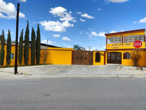 un bâtiment jaune avec des arbres devant une rue dans l'établissement Hotel Posada Santa Elena, à Parras de la Fuente