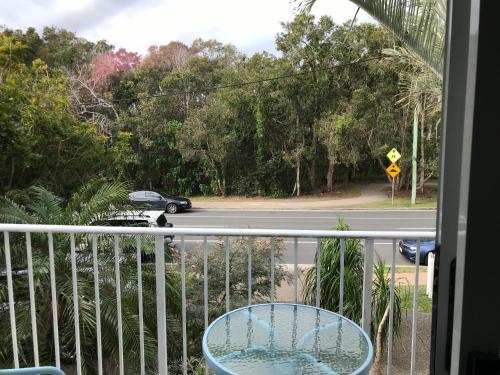 a balcony with a table and a car on the road at Mudjimba Esplanade Villa in Mudjimba