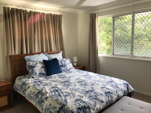 a bedroom with a bed with a blue and white comforter at Mudjimba Esplanade Villa in Mudjimba