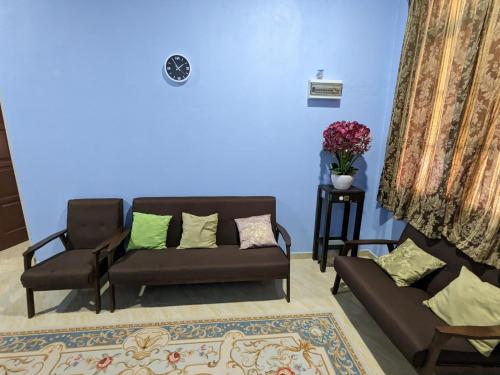 a living room with two couches and a blue wall at Mufeed Homestay in Kampong Wakaf Tengah