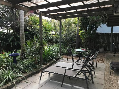 a patio with tables and chairs under a pergola at Mudjimba Esplanade Villa in Mudjimba