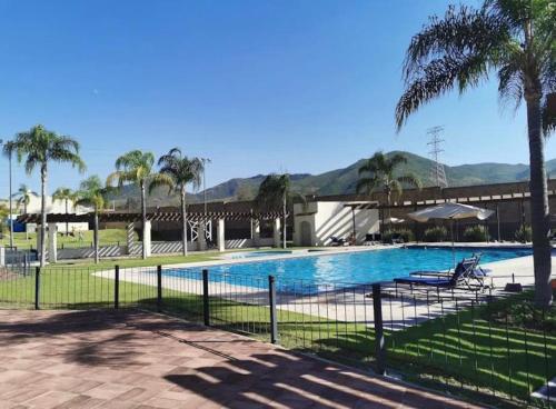 una piscina con palmeras y un complejo en Hermosa casa, sur de Guadalajara, en Guadalajara