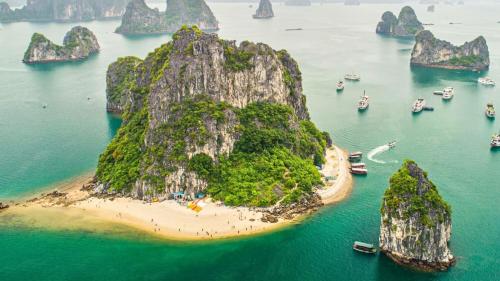 une île dans l'eau avec des bateaux et des montagnes dans l'établissement Victory Star Cruise, à Hạ Long