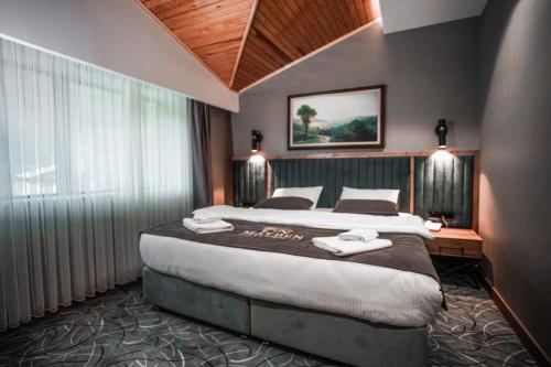 a bedroom with a large bed and a large window at Mayben Otel UZUNGÖL in Çaykara