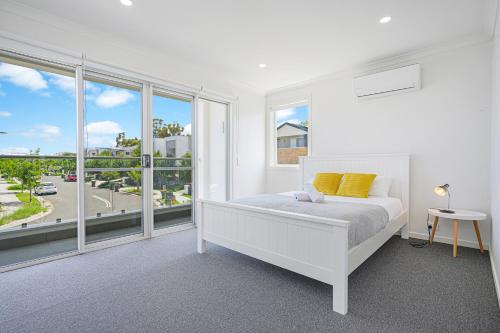 a white bedroom with a bed and large windows at Denham Court Adorable 4Br house with Wifi &Parking in Horningsea Park