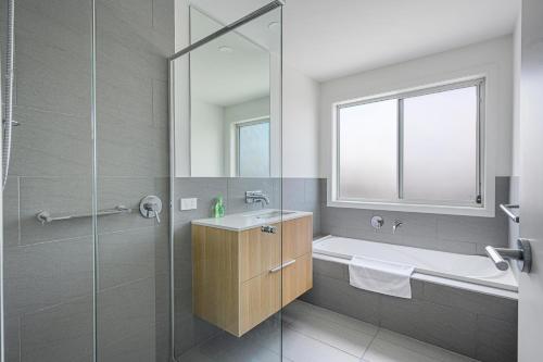 a bathroom with a tub and a sink and a shower at Denham Court Adorable 4Br house with Wifi &Parking in Horningsea Park