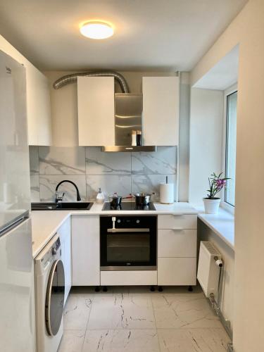a kitchen with white cabinets and a dishwasher at Grīzupes apart in Liepāja