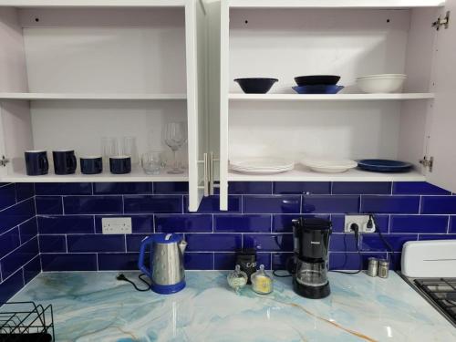 a kitchen with blue tiled walls and white cabinets at Chalet Belizomi Tropical Villa #1 in Gros Islet