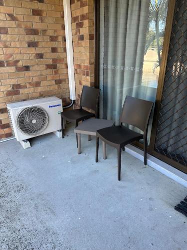 two chairs and a fan sitting next to a building at Bribie Waterways Motel in Bongaree
