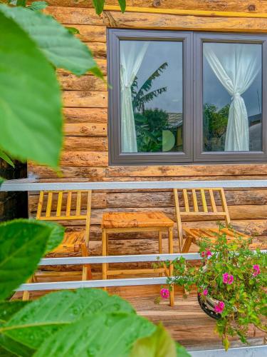 two chairs and a window on a log cabin at Lacasa home&coffee Mộc Châu in Mộc Châu
