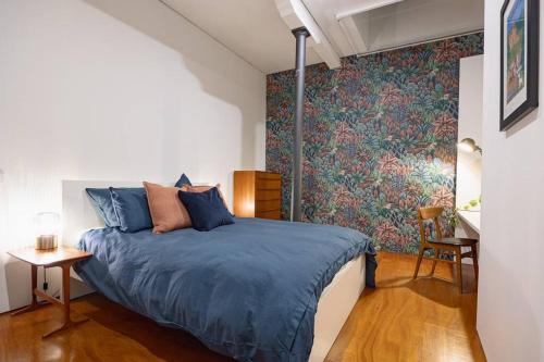 a bedroom with a bed with a blue comforter at The Penthouse on Gertrude St - Fitzroy in Melbourne