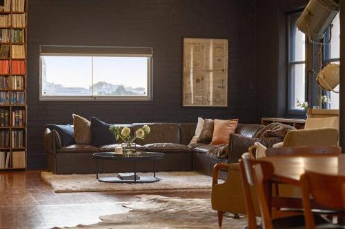 a living room with a brown couch and a table at The Penthouse on Gertrude St - Fitzroy in Melbourne