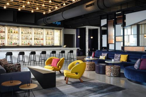 a lobby with yellow chairs and a bar withools at Aloft Knoxville West in Knoxville