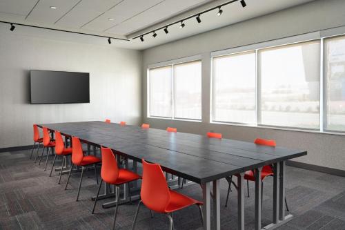 a conference room with a large black table and red chairs at Aloft Knoxville West in Knoxville