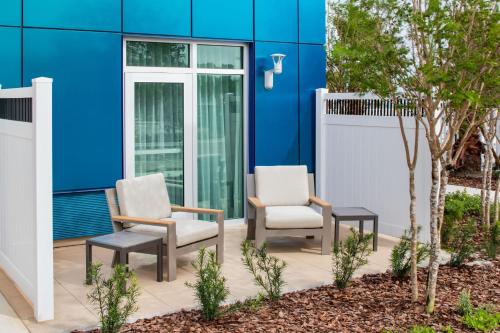 two chairs on a patio in front of a blue building at Courtyard By Marriott Titusville Kennedy Space Center in Titusville
