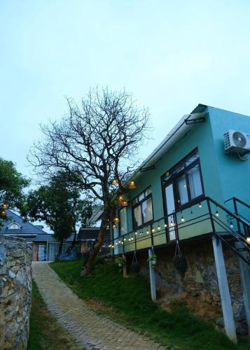 a blue house with a tree on the side of it at Lacasa home&coffee Mộc Châu in Mộc Châu