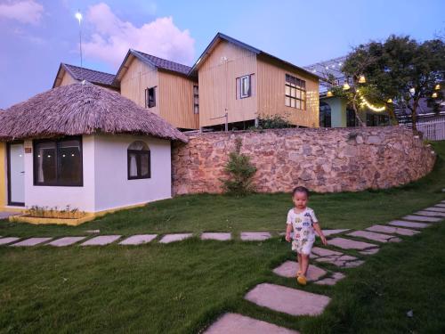 a little boy walking on stepping stones in front of a house at Lacasa home&coffee Mộc Châu in Mộc Châu