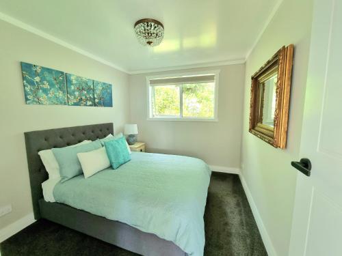 a bedroom with a bed with blue pillows and a window at Red Rock Cottage, beachfront luxury in Clarks Beach