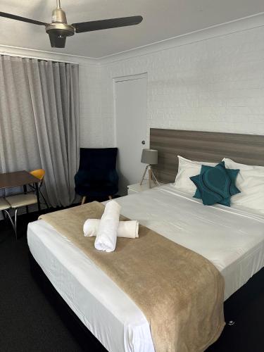 a bedroom with a large bed with towels on it at Bribie Waterways Motel in Bongaree