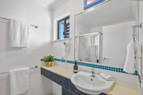 a white bathroom with a sink and a mirror at Noosa River Walk - Unit 107 in Noosaville