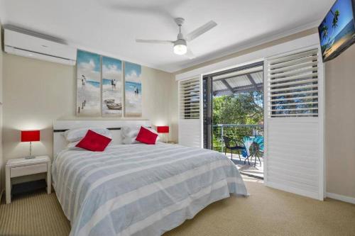 a bedroom with a bed with red pillows and a window at Noosa River Walk - Unit 107 in Noosaville