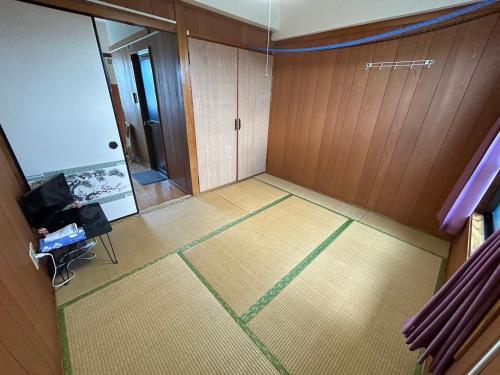 een lege kamer met een deur en een vloer bij 民宿ちねん in Uruma