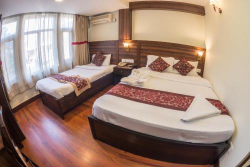 a hotel room with two beds and a window at Hotel Yambu kathmandu in Kathmandu