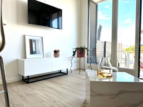 a living room with a white cabinet and a tv on a wall at Marina Dream House in Lignano Sabbiadoro