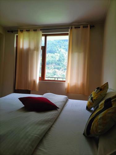 a bedroom with a large bed with a window at Farm Hostel & Camps in Manāli