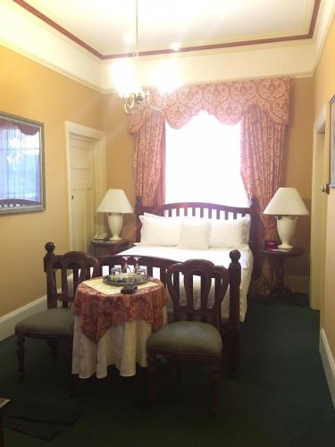 a bedroom with a bed with a table and chairs at Clifton Motel & Grittleton Lodge in Bunbury