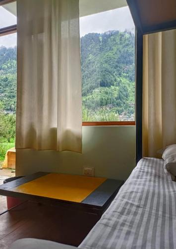 a bed in a room with a large window at Farm Hostel & Camps in Manāli