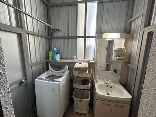 een kleine badkamer met een wasmachine en een wastafel bij 民宿ちねん in Uruma