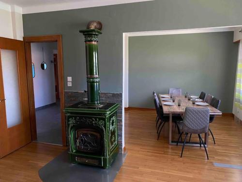 um fogão verde numa sala de jantar com uma mesa em Gîte Le p’tit Mintz em Natzwiller