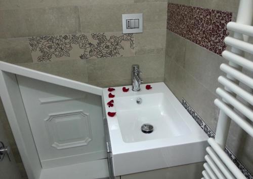 un bagno con lavandino bianco con fiori rossi di Mansarda Palatina a Torino