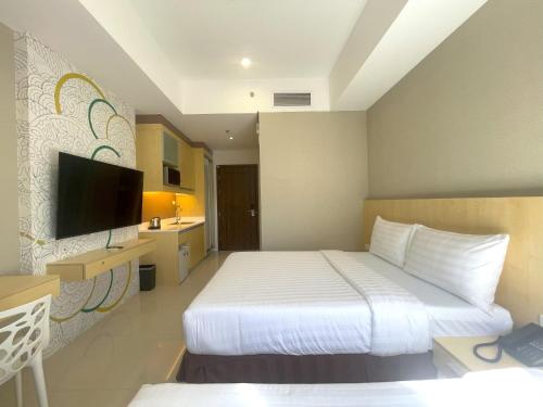 Habitación de hotel con cama y TV de pantalla plana. en Hotel101 - Fort, en Manila