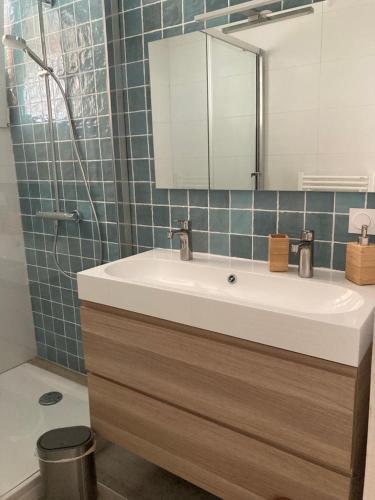une salle de bain avec un lavabo et un miroir dans l'établissement La Canaulaise, à Lacanau