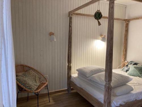 une chambre avec un lit à baldaquin et une chaise dans l'établissement La Canaulaise, à Lacanau