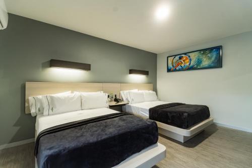 una habitación de hotel con 2 camas y un cuadro en la pared en HOTEL LEMON GREEN -Zona Expo Frente al Centro de Convenciones en Guadalajara