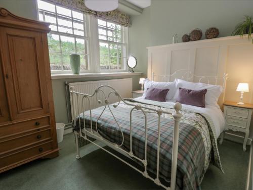 ein Schlafzimmer mit einem weißen Bett und einem Fenster in der Unterkunft Trefoil Cottage in Biggar