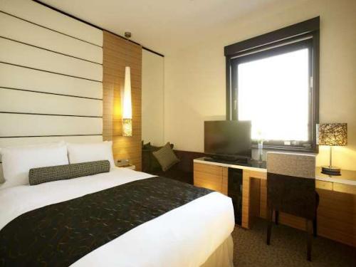 a bedroom with a bed and a desk and a window at Hotel Trusty Osaka Abeno in Osaka