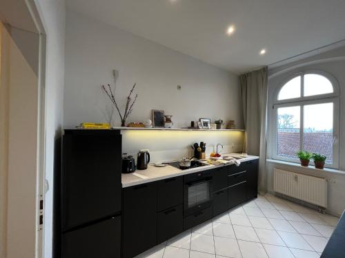 a kitchen with black cabinets and a window at MOKA Living-Sunset Apt, Nordic Design,Küche,WLAN, SmartTV in Magdeburg