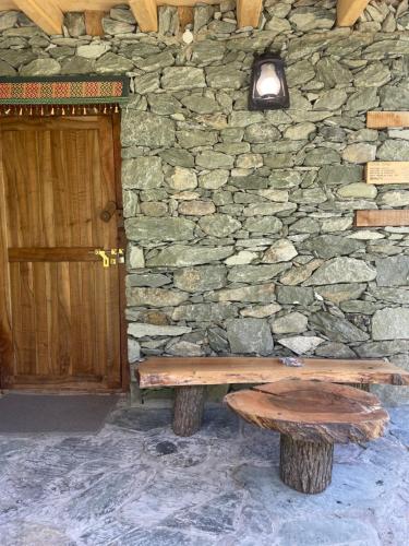 a wooden bench sitting in front of a stone wall at COSY STONES bY MANOKUR-E- BASA in Minapin